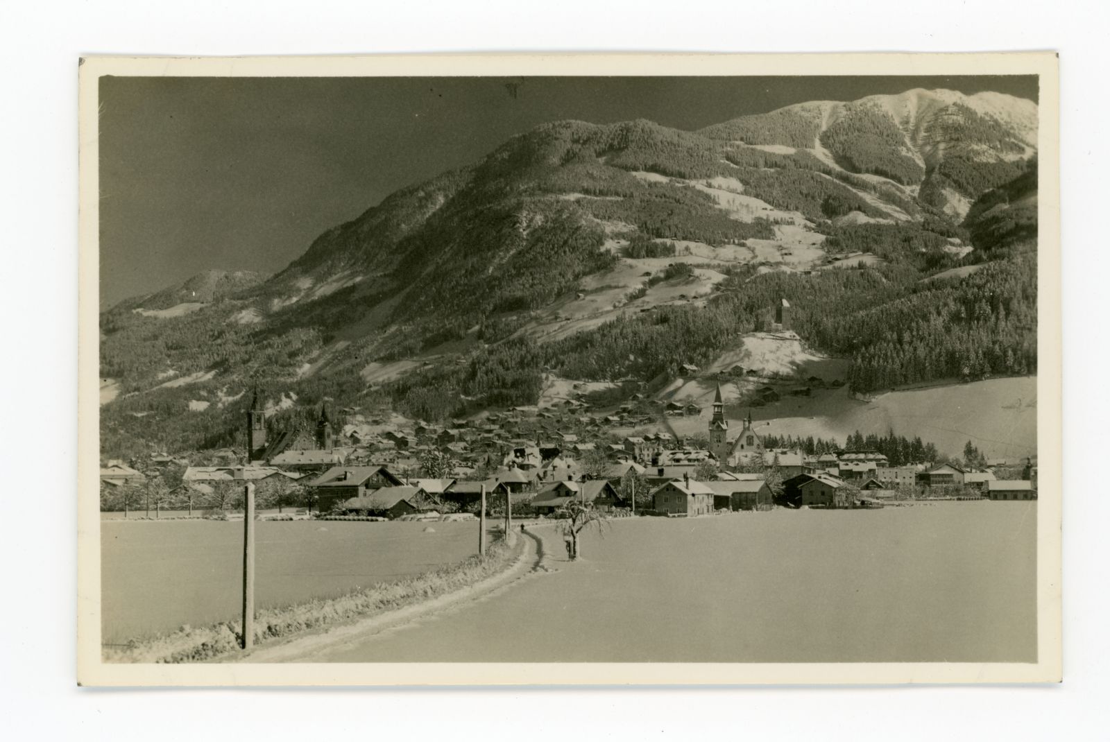 Blick Richtung Burg Freundsberg vom Tal aus im Winter, links im Vordergrund verschneiter Weg