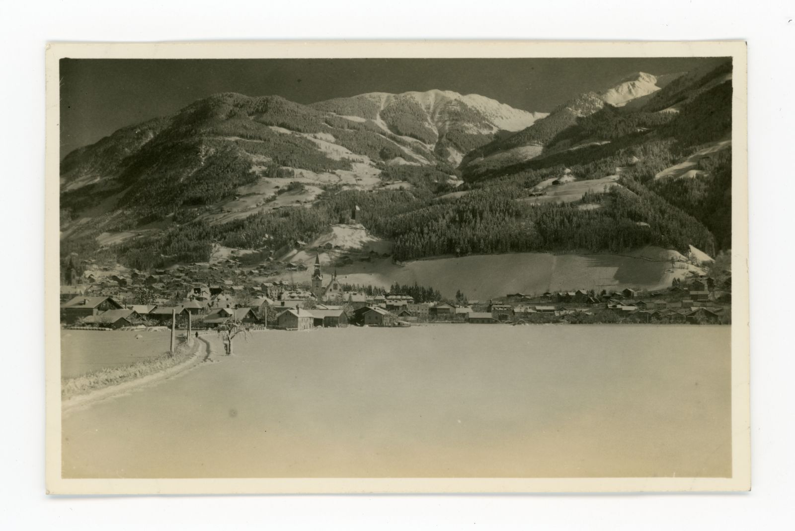 Blick vom Tal Richtung Burg Freundsberg im Winter, links verschneiter Weg und in der Ferne eine einsame Person