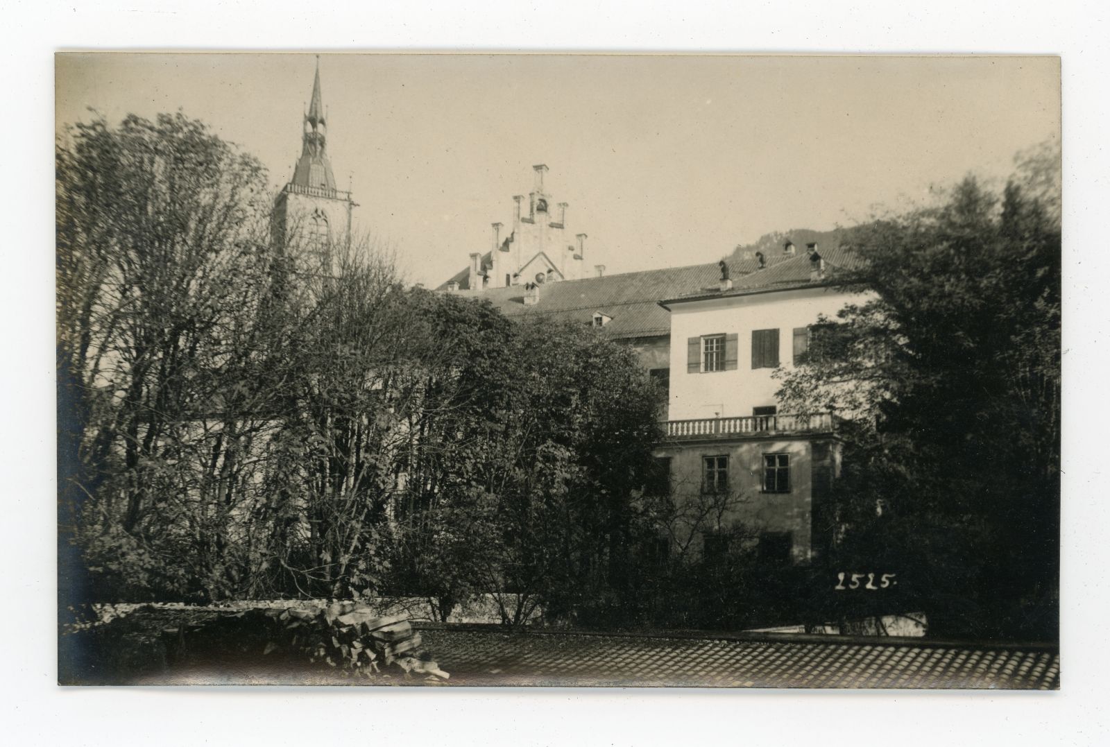 Schwaz, Holzhaufen links, davor Bäume und verdeckt im Hintergrund die Pfarrkirche Maria Himmelfahrt