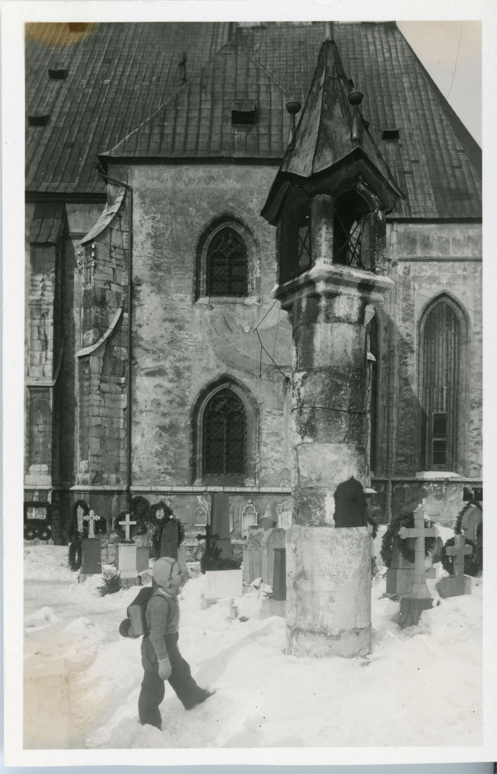 Friedhof bei Pfarrkirche mit Sakramentshäuschen und Schulkind im Schnee