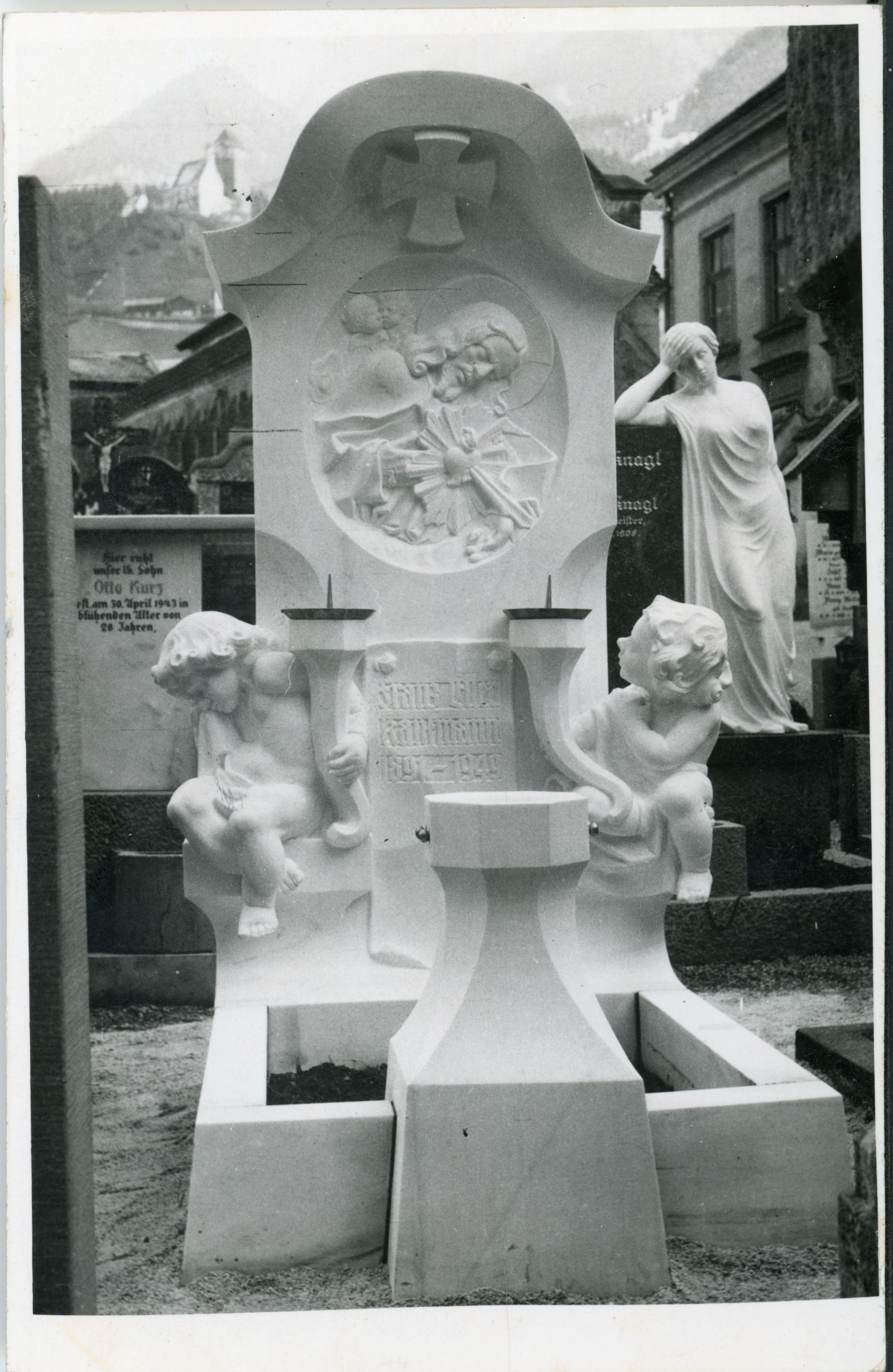 Schwaz, weisses Marmorgrab, Christus in Relief mit Herz Jesu, unten zwei trauernde Laternenputti