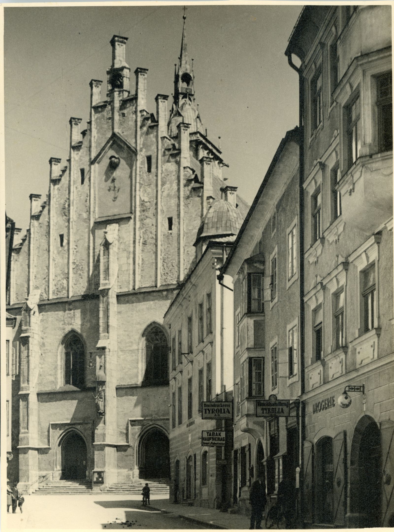 Schwaz, Eingangsbereich der Pfarrkirche mit Geschäftsstraße, Tyrolia, Drogerie, Tabakgeschäften etc.