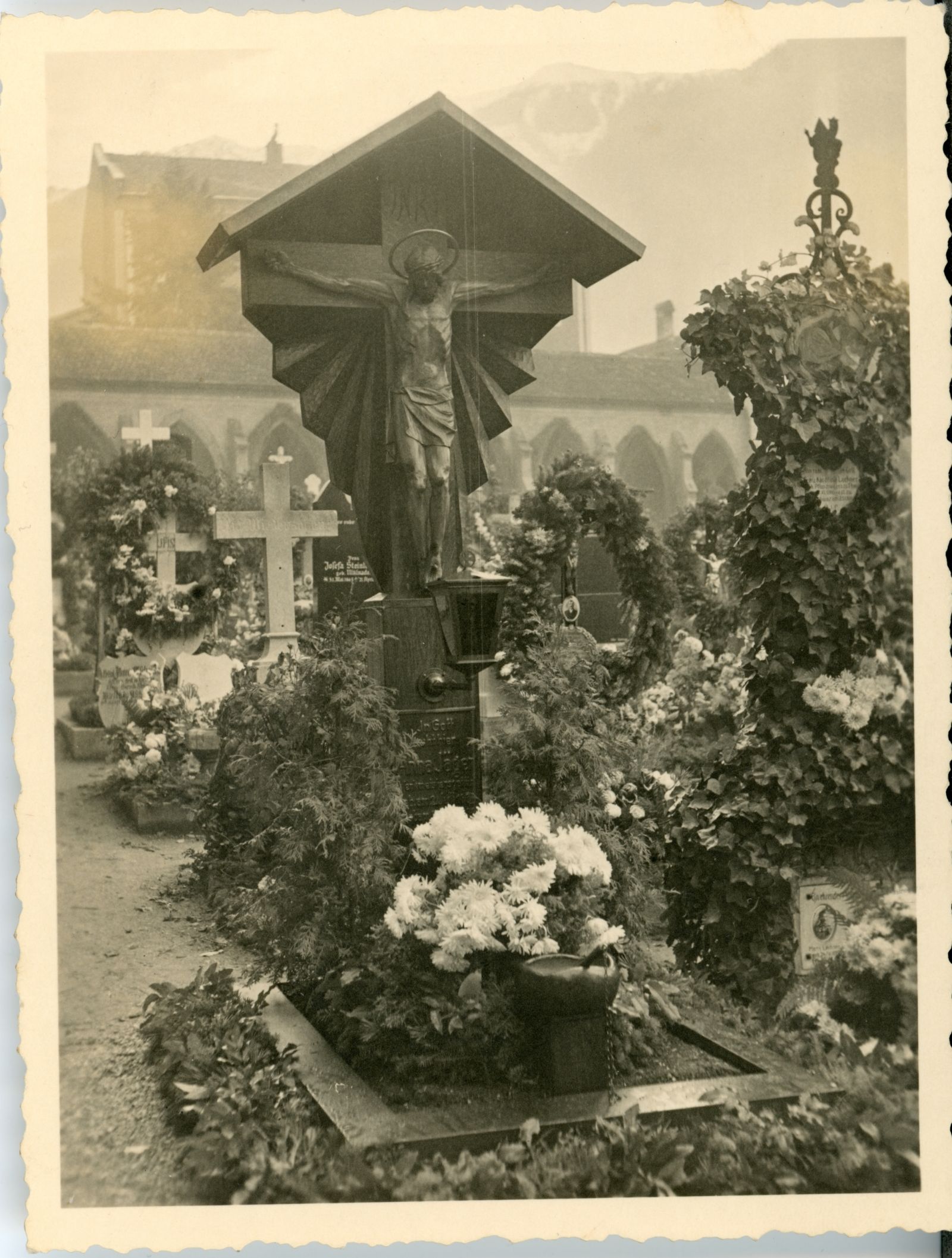 Friedhof mit hölzernem Kruzifix und klassischem immergrünem Blumenschmuck