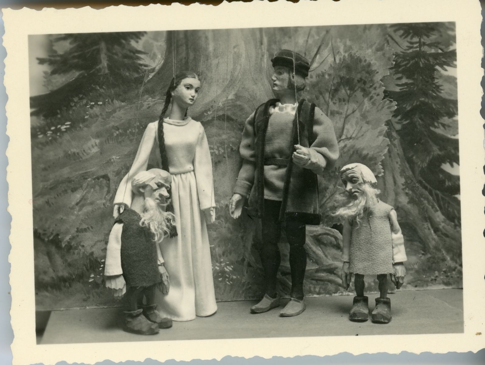 Marionettenfiguren vor Baum im Wald, Schneewittchen mit Prinz (oder Jäger?) und 2 Zwerge.