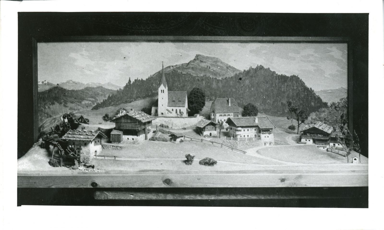 Kirche mit Bauernhöfen in gebirgiger Landschaft